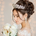 Wedding Hairstyle in a short dress with lace in the crown earrings. Wedding bouquet